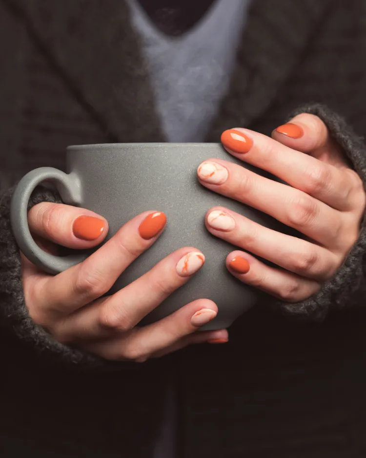 nail art marbré et féminin sur des ongles courts en orange laiteux