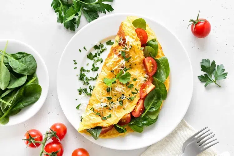 omelette aux épinards facile à préparer garnie de tranches de tomate et de fromage râpé