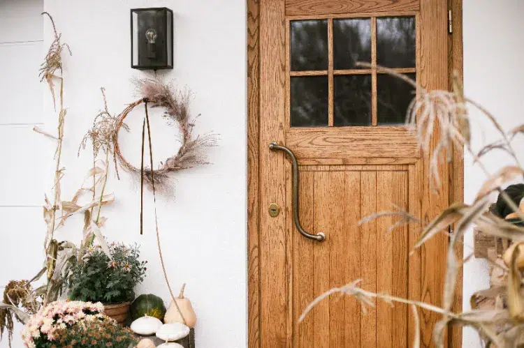 déco de porche automnale avec des chrysanthèmes et une couronne de pampa