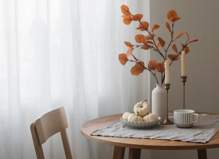 décoration d'automne scandinave avec des courges blanches et des feuilles sèches sur la table à manger