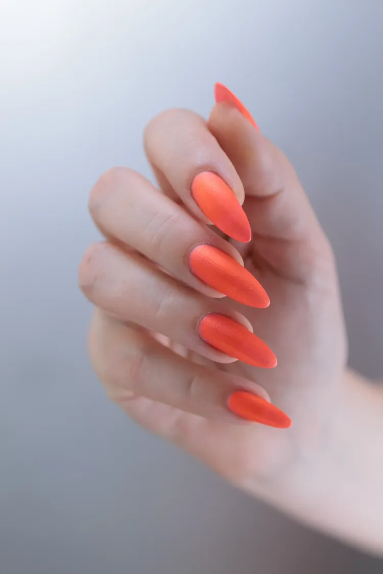 des ongles longs en amande décorés d'un vernis orange mat