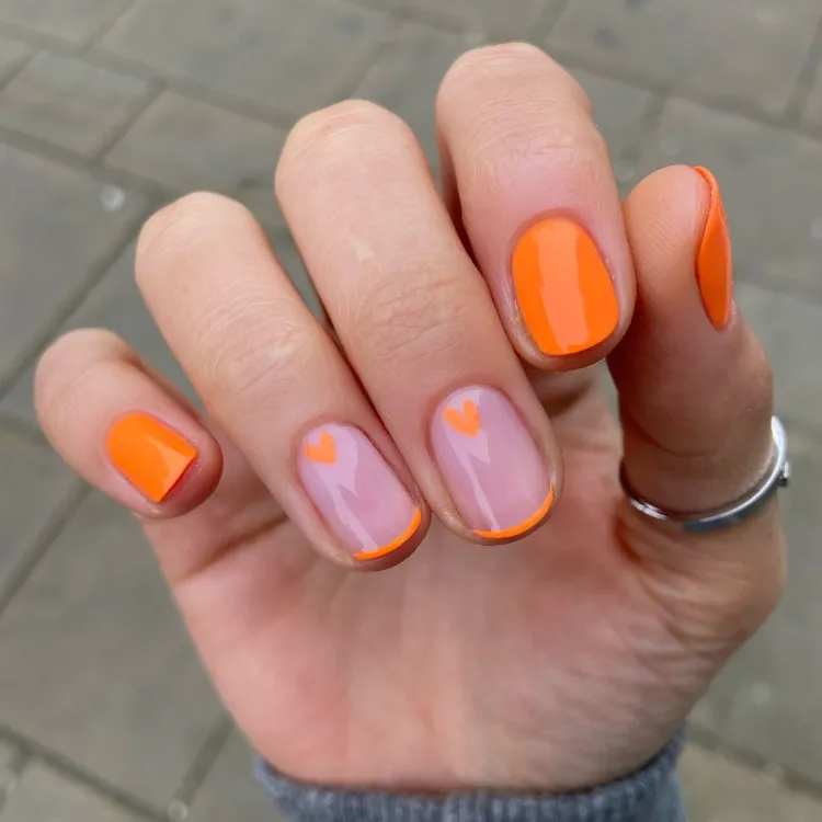 une idée de manucure orange avec un nail art délicat pour l'automne 2024