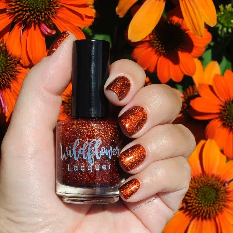 une idée de manucure orange en automne avec un vernis pailleté