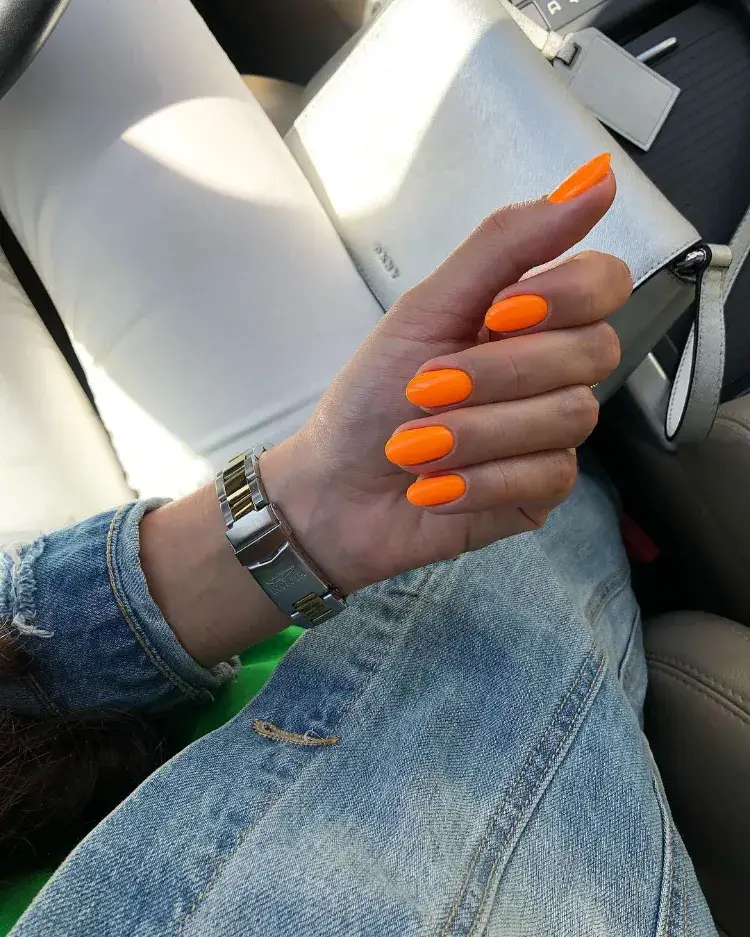 une jolie manucure en orange néon sur des ongles ovales