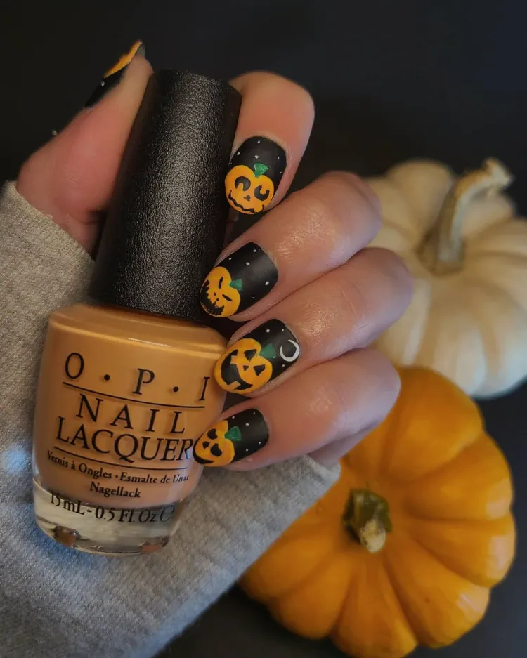 une idée de jack o' lantern nail art sur des ongles noirs