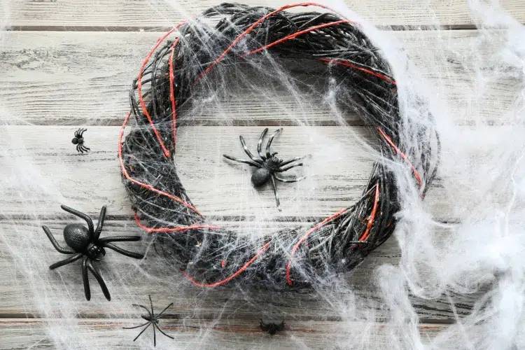 une idée originale de couronne d'halloween diy avec des branches peintes en noir et des araignées