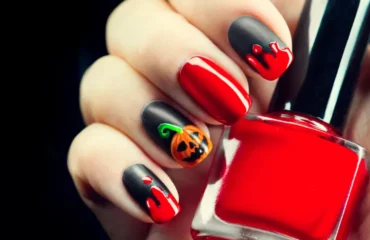 une manucure d'halloween osée en noir et rouge avec un motif de jack o'lantern