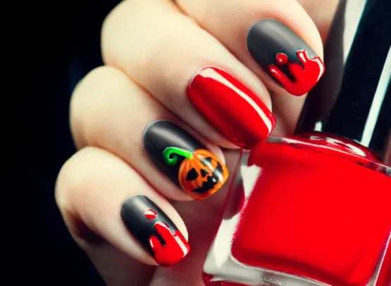 une manucure d'halloween osée en noir et rouge avec un motif de jack o'lantern