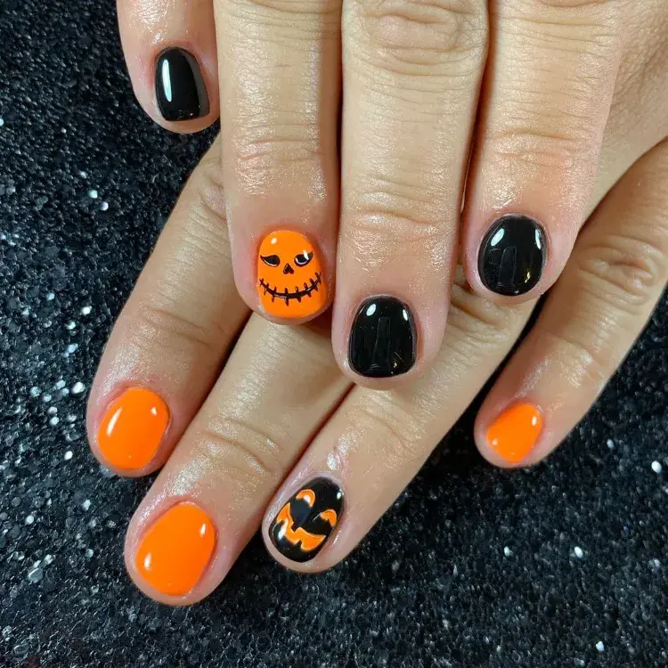 une manucure pour ongles courts en noir et orange sur le thème jack o' lantern