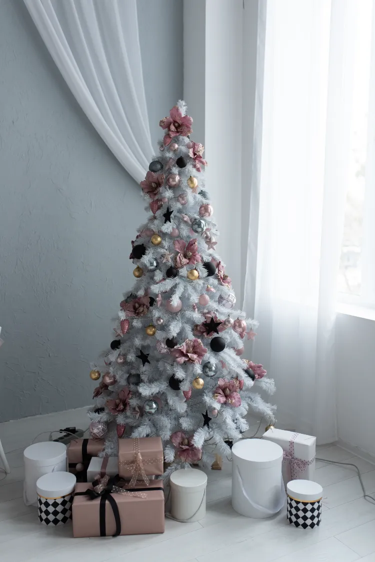 comment décorer un sapin enneigé avec des décorations en rose noir et doré de style moderne