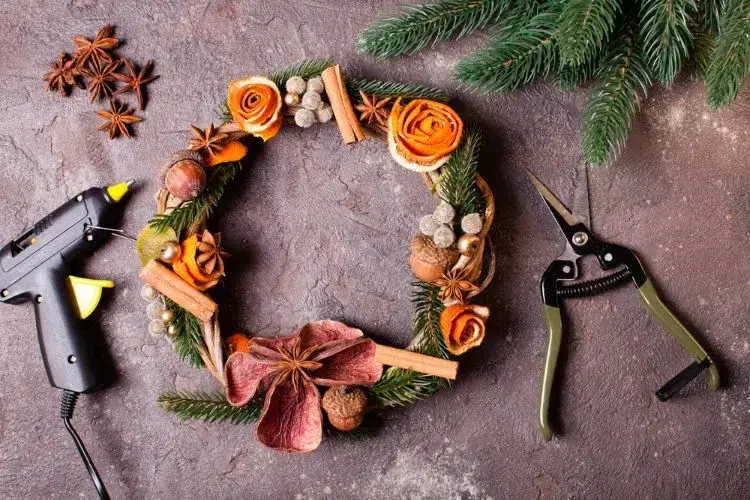 une couronne de noël naturelle décorée de roses de pelures d'orange bâtonnets de cannelle glands et anis étoilé