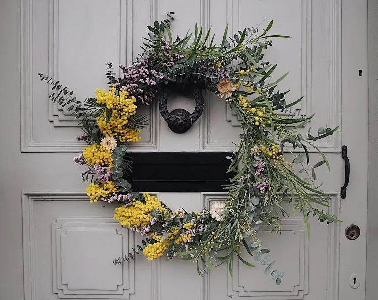 une idée de décoration pour la porte d'entrée avec une couronne d'eucalyptus mimosa et fleurs