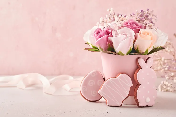 décoration de pâques avec un beau bouquet de fleurs roses dans un vase, des œufs de pâques et un lapin.