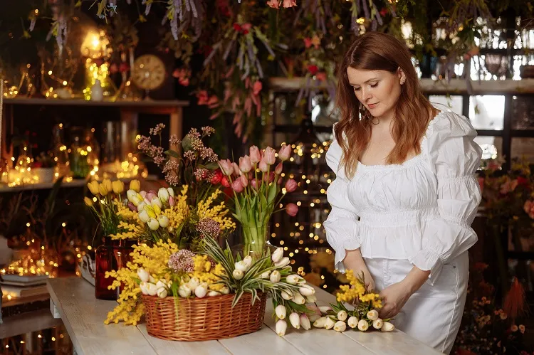 une jeune fleuriste s'occupe des fleurs dans un magasin de fleurs chaleureux.