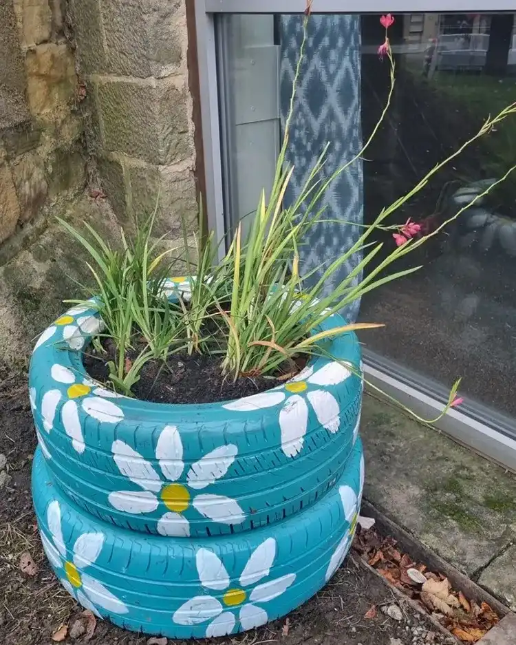 des pneus peints et empilés qui font office de jardinière insolite