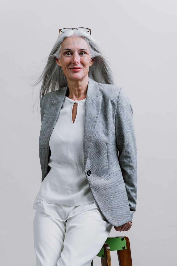 Belle femme âgée en tenue de travail avec un pantalon blanc et chemise en chifon blanche