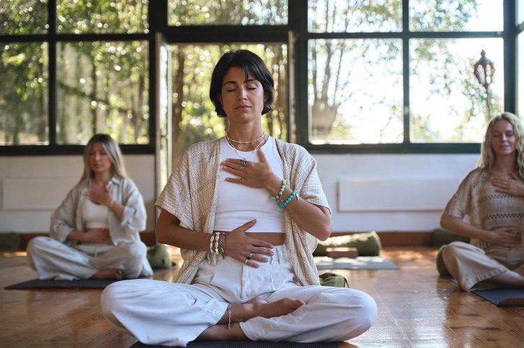 young women group meditating doing breathing exercises at yoga session.