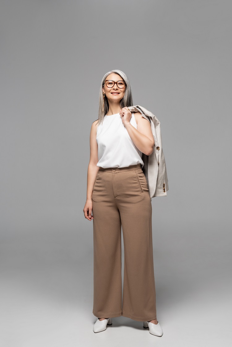 femme d'affaires asiatique heureuse en lunettes, pantalon beige et haut blanc