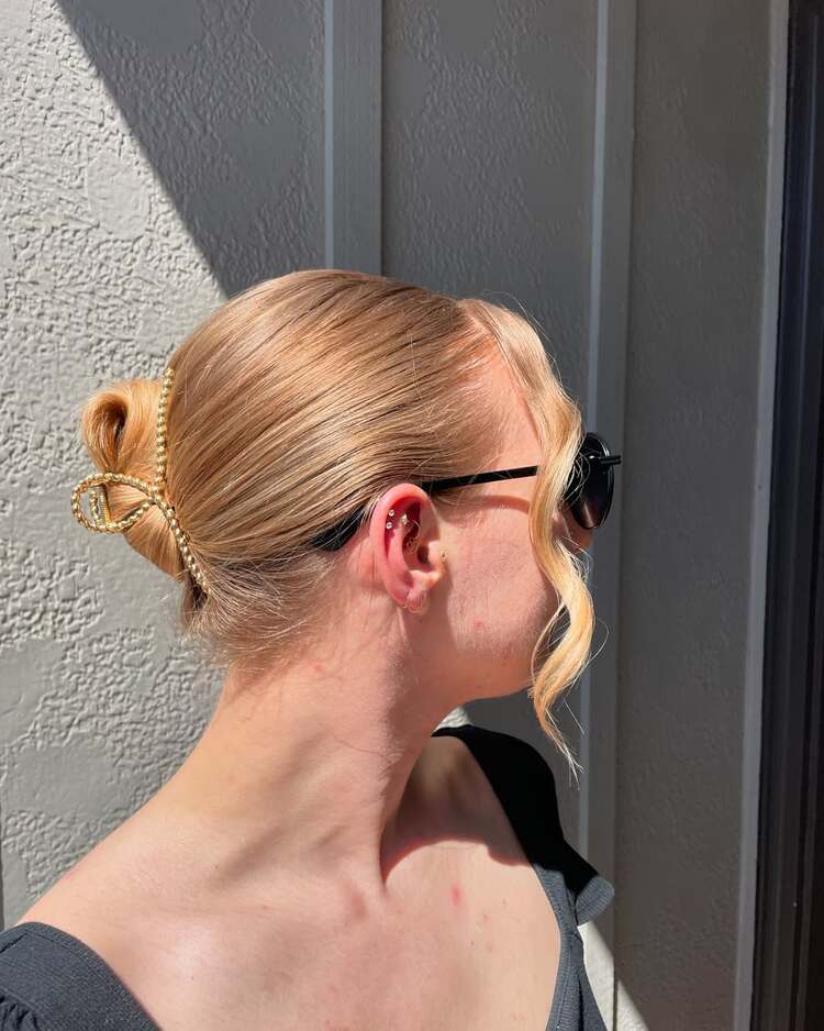 chignon bas lissé accessoirisé avec une pince dorée en forme de nœud
