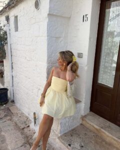 les accessoires dorées renforcent l'allure chic de la robe bustier jaune pâle qui sent bon l'été