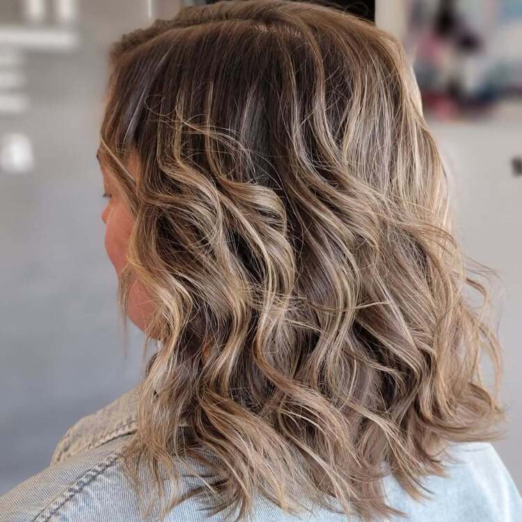 des cheveux wavys et bohèmes mis en valeur par des mèches caramel doré