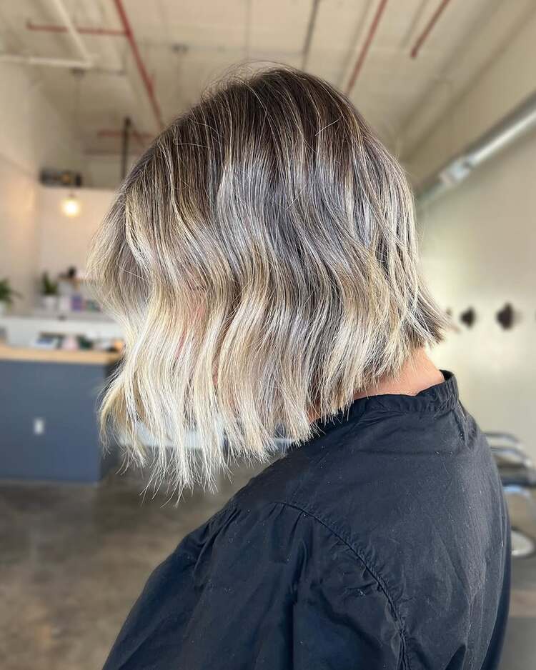 un carré clavicule texturé avec des reflets blond cendré et des ondulations légères un style effortless chic por l'été