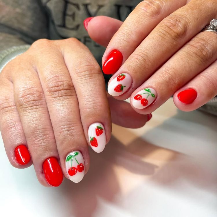 une jolie manucure rouge et blanche sur ongles courts avec nail art fruité cerises et fraises