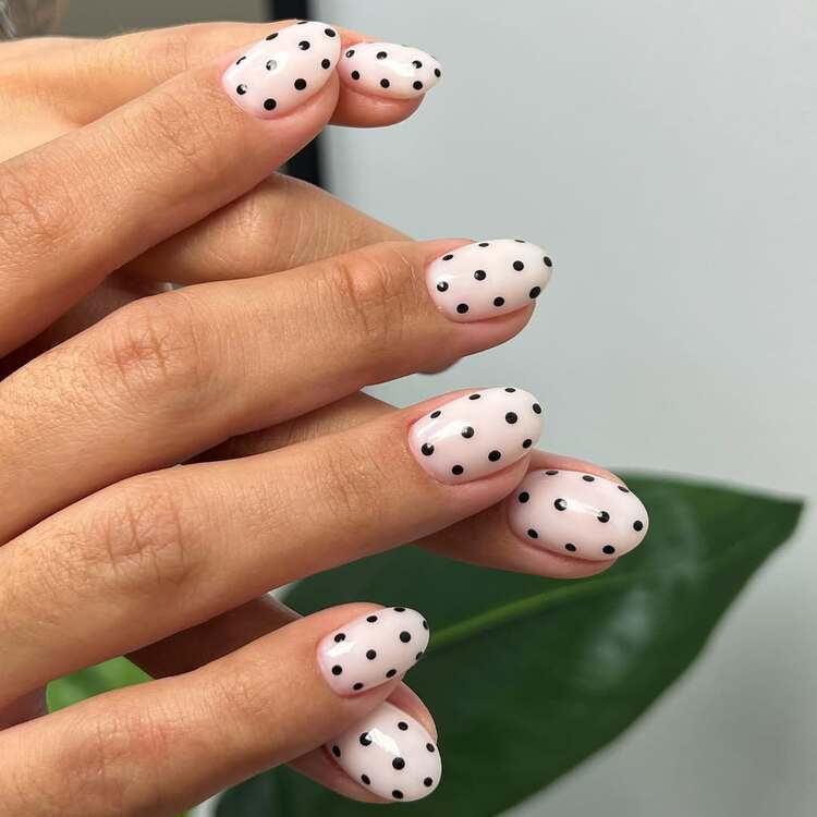 manucure à pois noirs sur fond nude qui propose un look minimaliste parfait pour les ongles courts