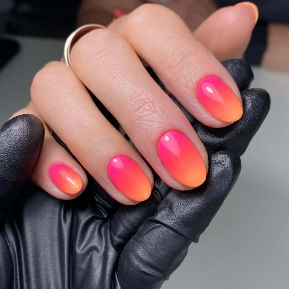 Ongles courts et arrondis sublimés par un ombré rose et orange fluo - un effet dégradé lumineux