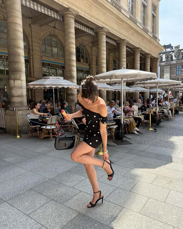 une mini robe noire à gros pois blancs et aux épaules dénudées, parfaite pour une allure chic et féminine