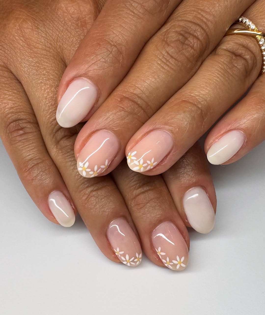 des ongles ovales, base laiteuse et petites fleurs pour une manucure d'été femme 60 ans