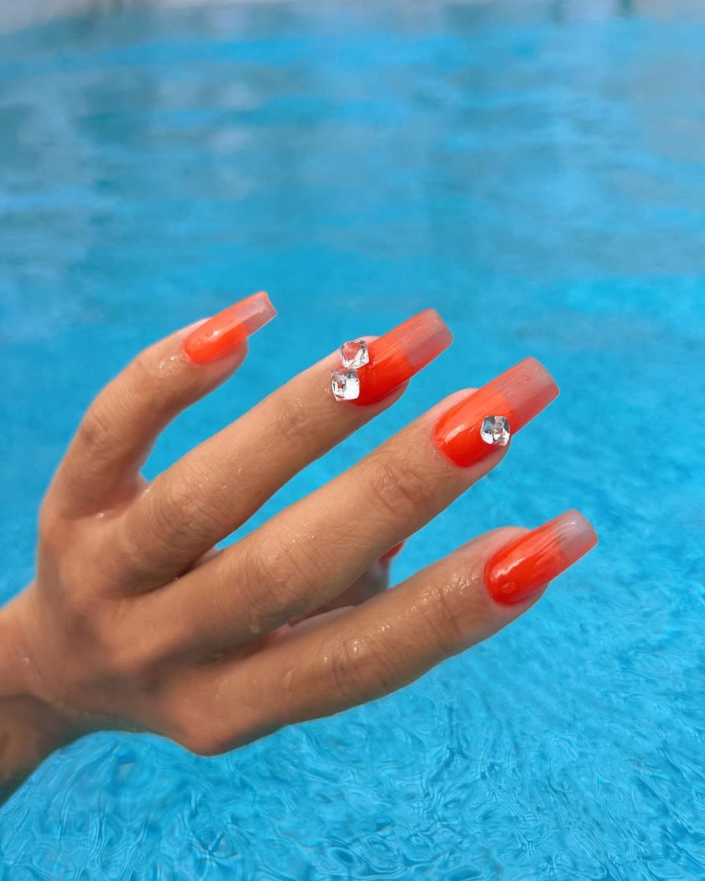 des strass glaçons et vernis orange vif pour réaliser une manucure Aperol Spritz insolite