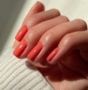 la manucure d'été femme 60 ans prône la teinte corail, les ongles courts
