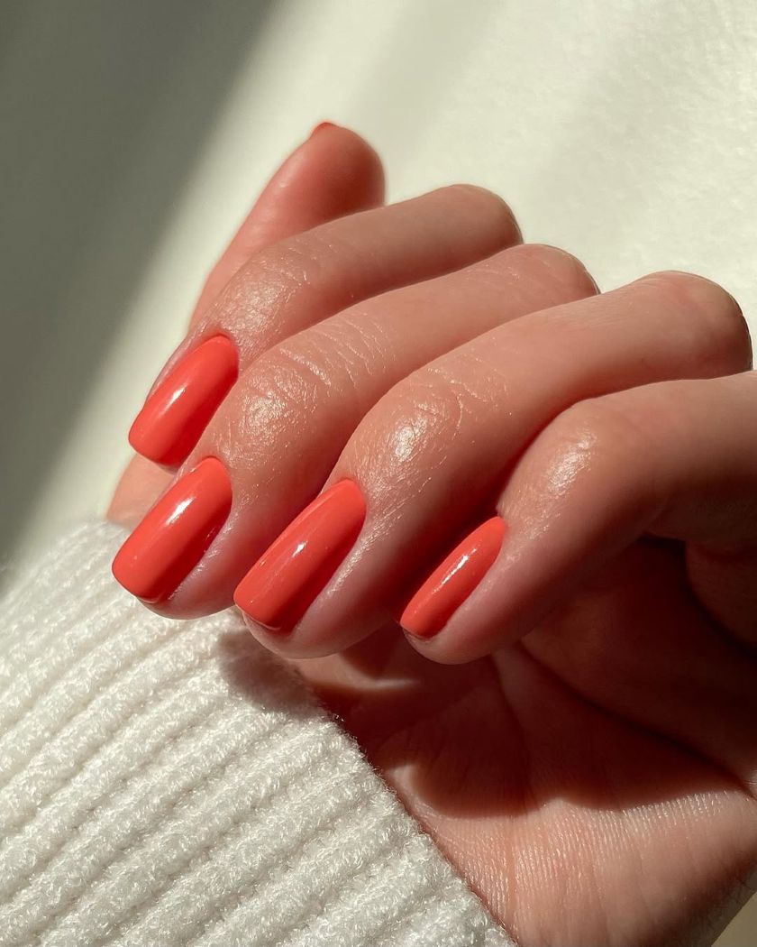 la manucure d'été femme 60 ans prône la teinte corail, les ongles courts et ovales