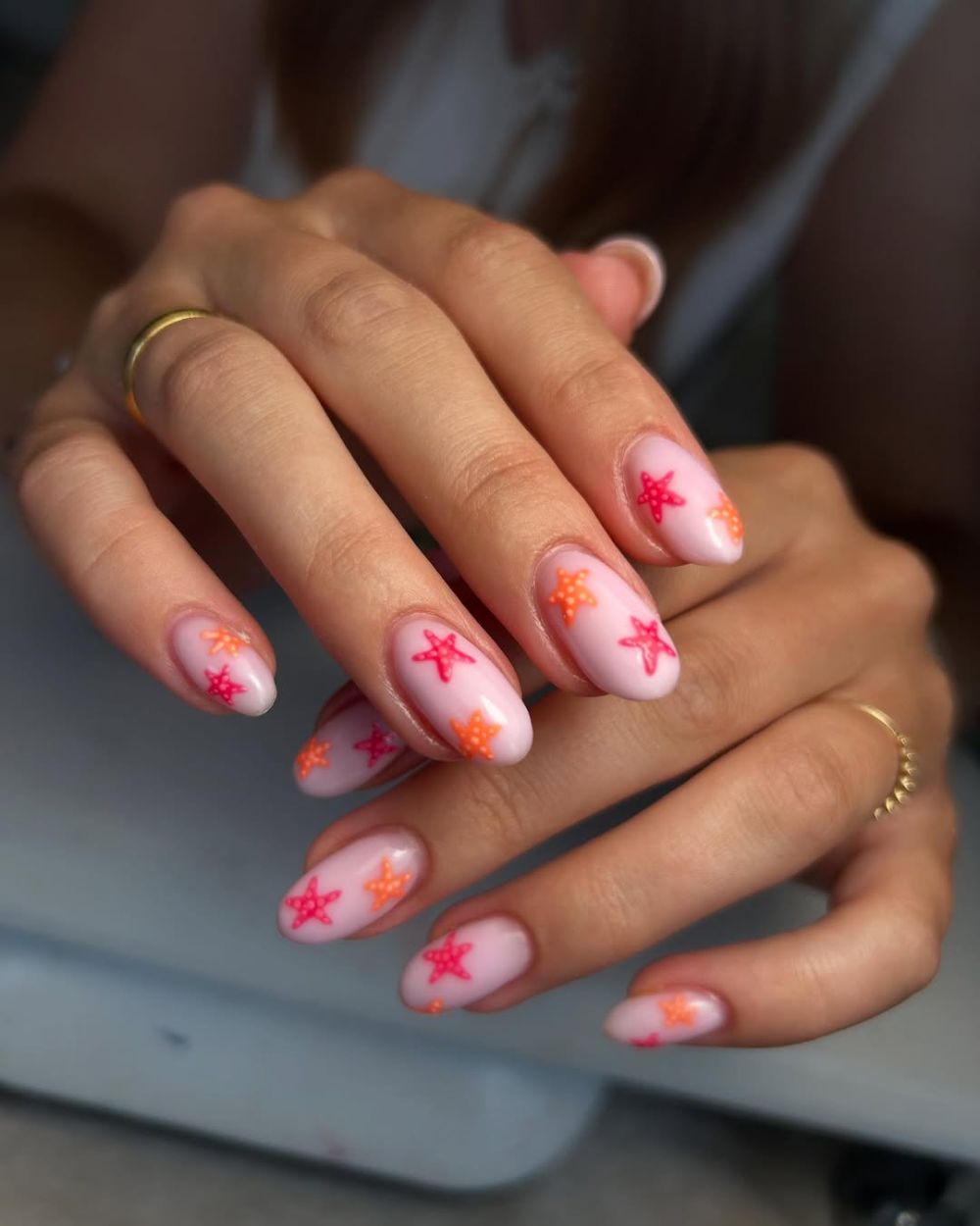 nail art étoile de mer en rouge et orange sur ongles nude en amande