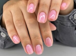 Ongles courts, doux et brillants évoquant le minimalisme raffiné et la manucure bien soignée