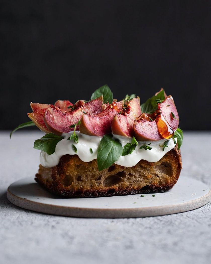 Toast aux pêches de vigne et au yaourt parsemé de feuilles de basilic