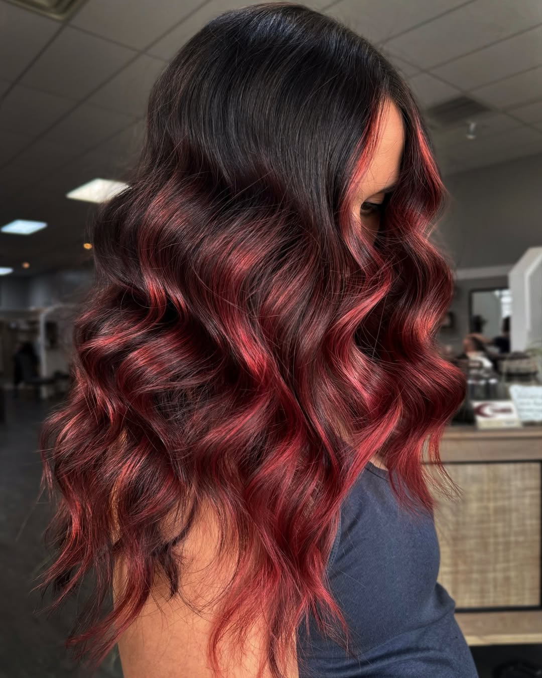 balayage rouge framboise sur des cheveux bruns pile dans la tendance coloration automne 2025