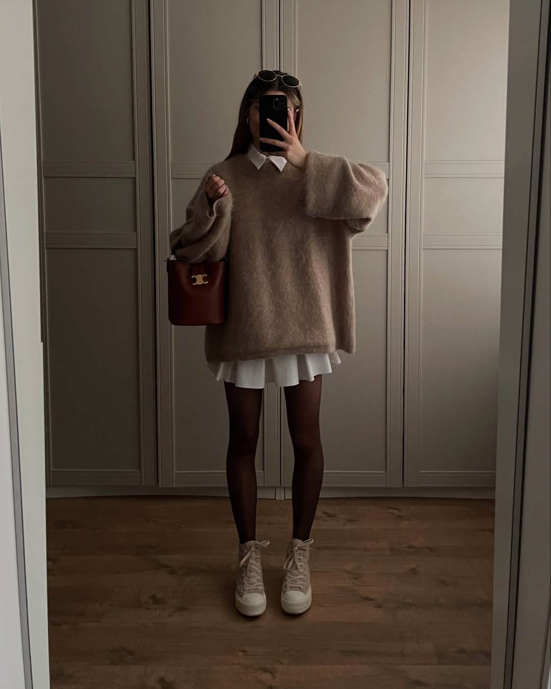 layering chic pour la rentrée-un pull oversize en beige associé à une chemise blanche longue et une jupe plissée assortie