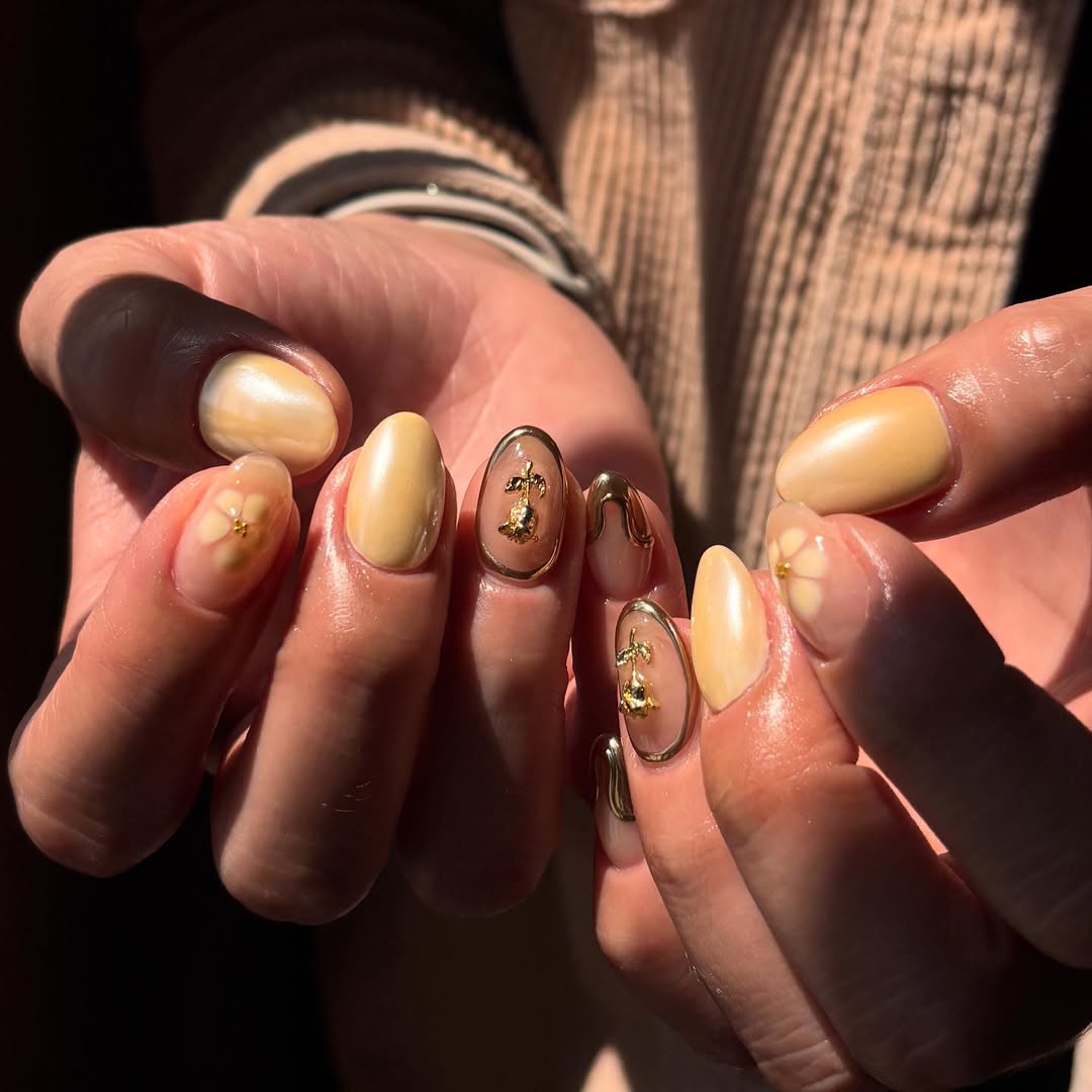 manucure jaune pastel sublimée par un nail art bronze