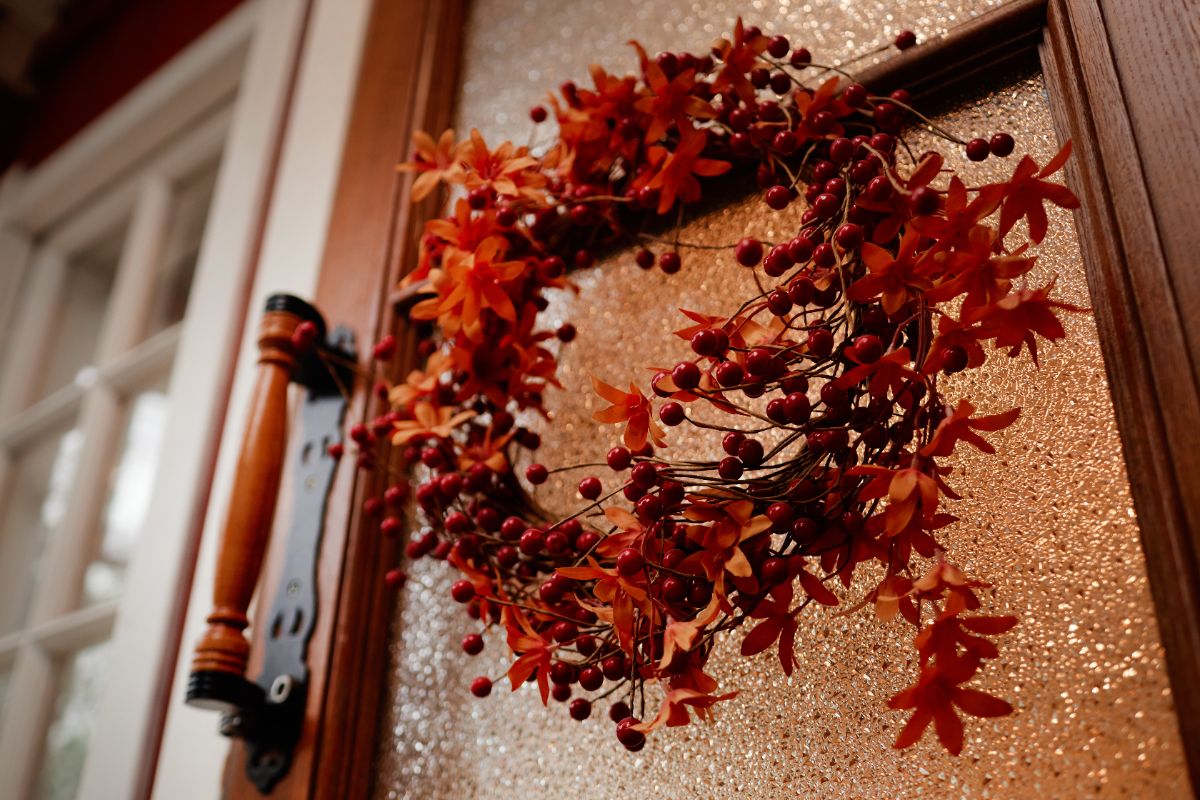 couronne automnale orange et rouge réalisée avec des branches feuilles et baies artificielles