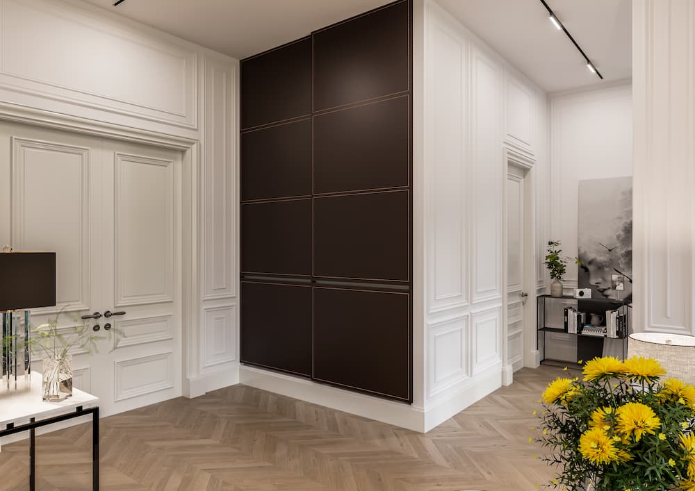 hall d'entrée élégant murs moulurés peints en blanc avec mur d'accent marron chocolat sol en parquet à chevrons bois clair