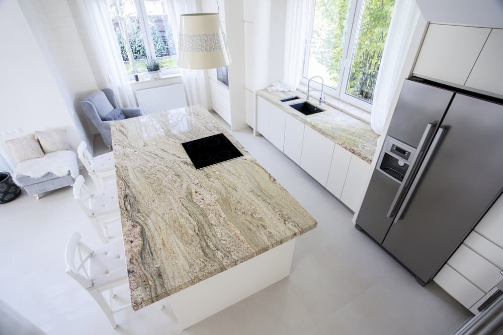 îlot central avec plan de travail en pierre naturelle aux tons beige et gris veinée de motifs organiques