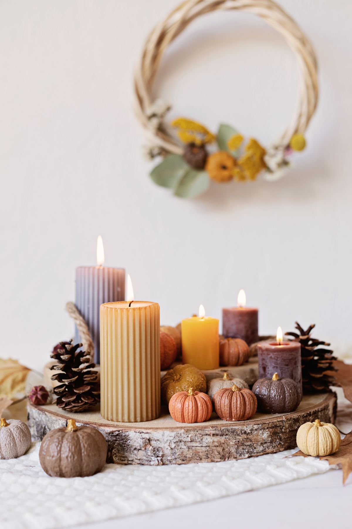 plateau en bois brut et composition de bougies et petites citrouilles en tant que déco automne lumineuse