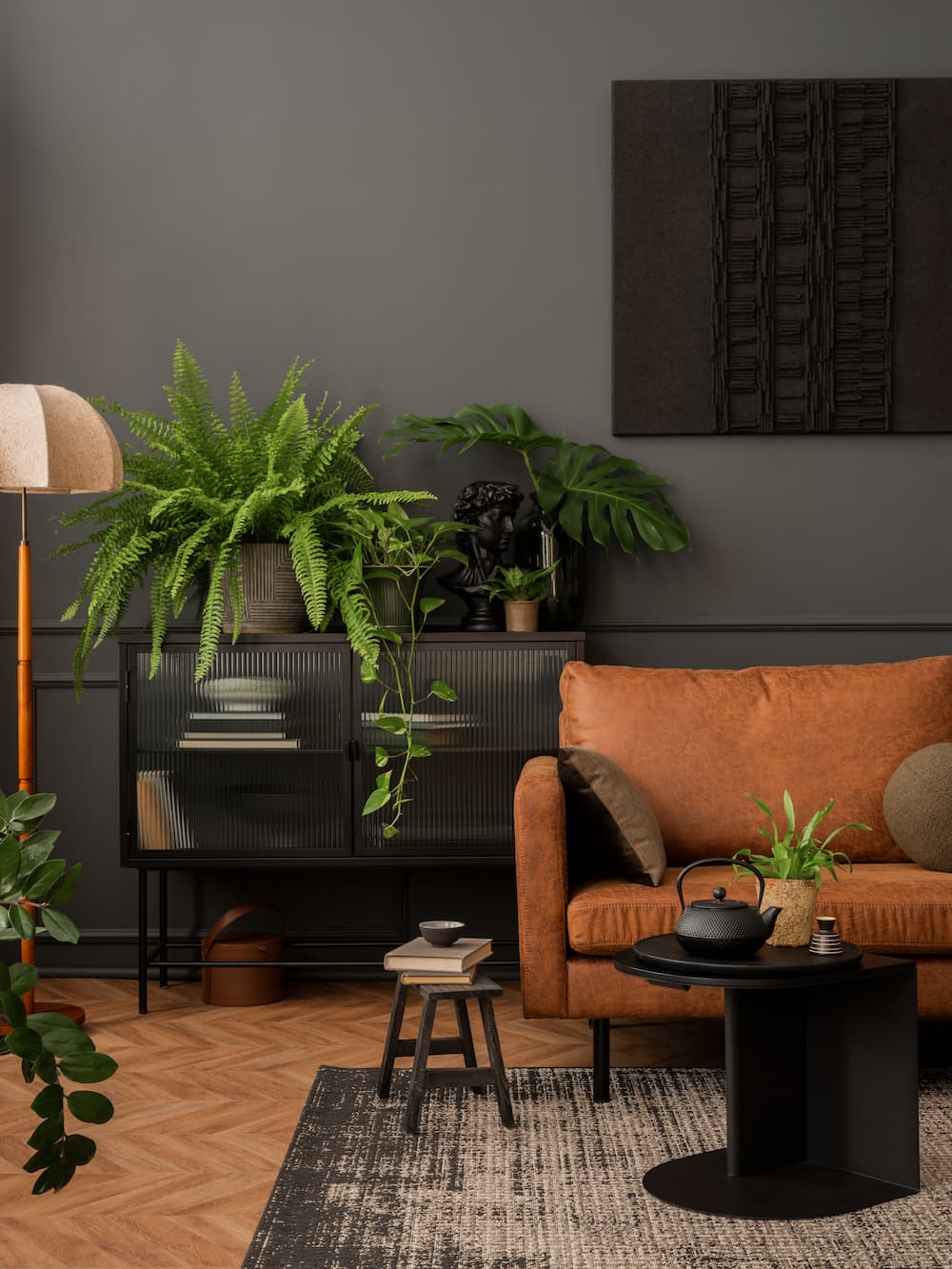 salon chaleureux et moderne mur marron chocolat canapé en cuir table basse noire en métalpetit tabouret en bois foncé