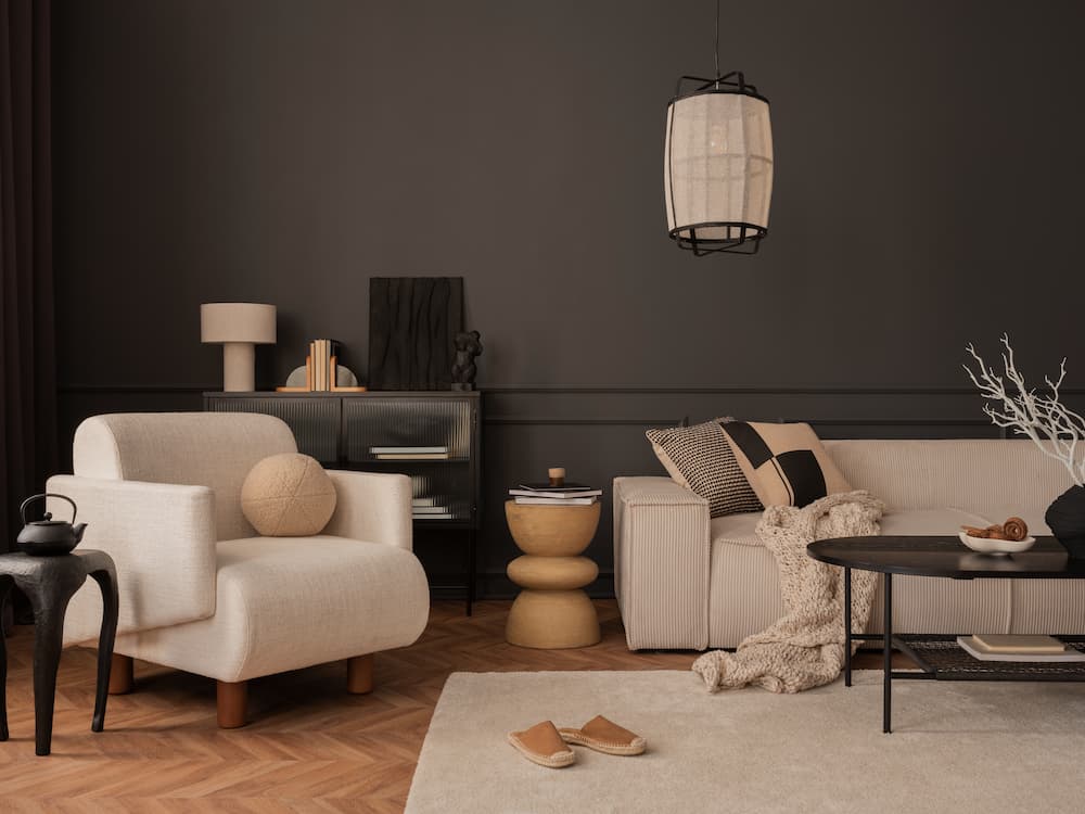 salon cosy et élégant murs peints en marron chocolat couleur année 2026 canapé et fauteuil en tissu beige crème, table basse ronde noire en métal
