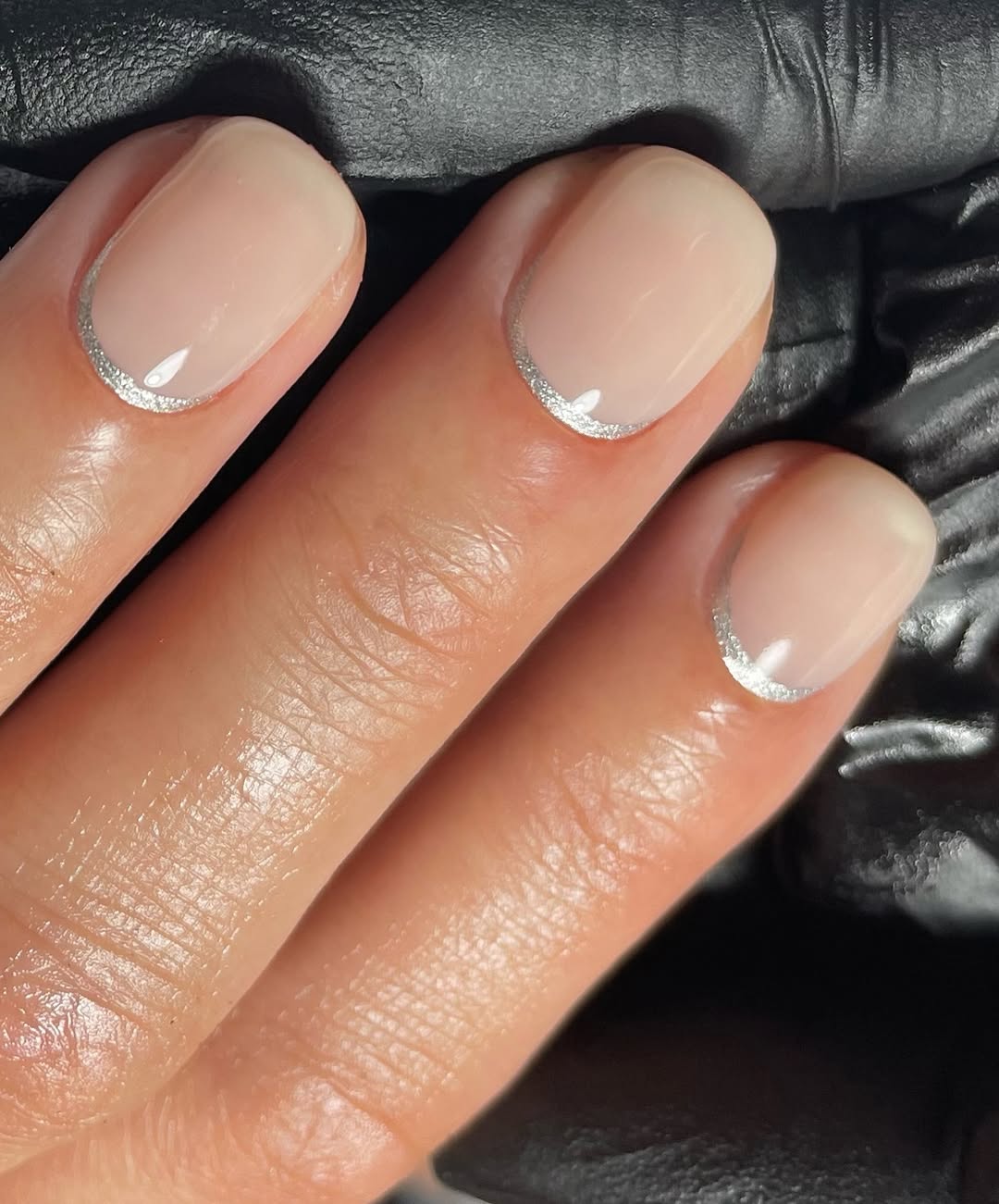 Des paillettes discrètes et une base laiteuse pour flatter les ongles très courts