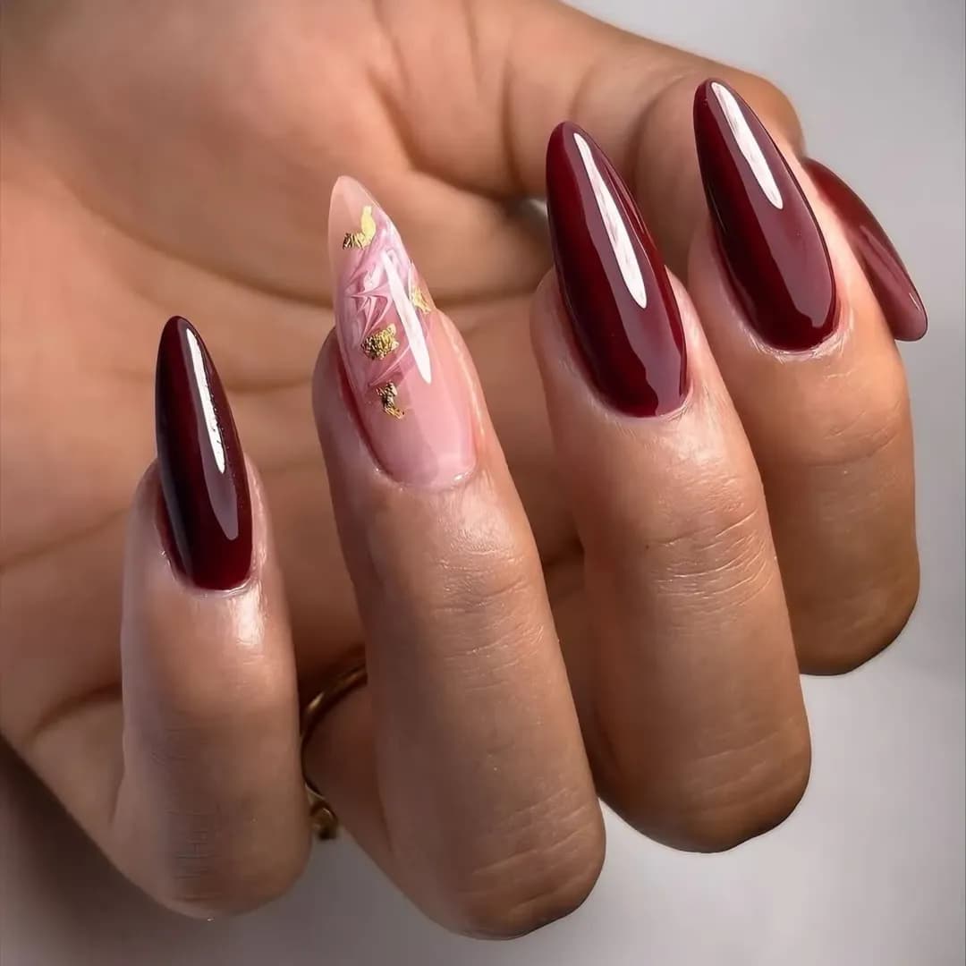 Un look élégant combinant vernis bordeaux et touches de feuilles d'or pour une finition luxueuse et romantique