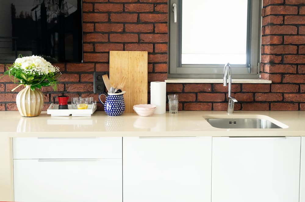 cuisine moderne mur en briques rouges meubles blancs et décorations colorées