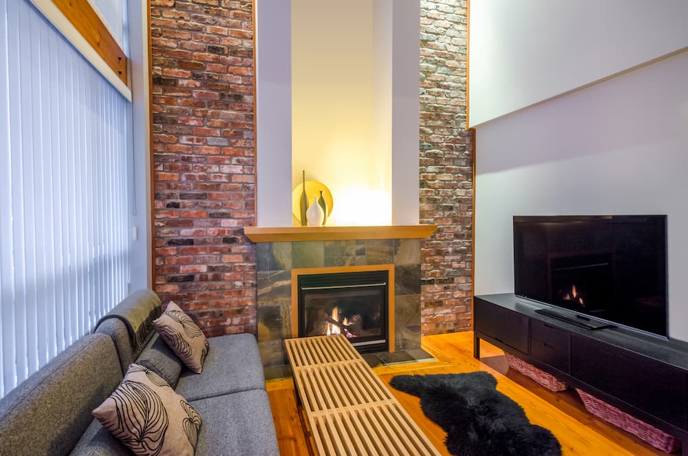 intérieur moderne cheminée encadrée de briques apparentes et surmontée d’une tablette en bois